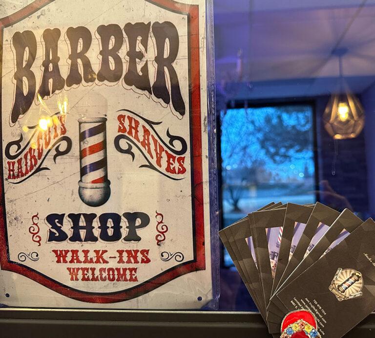 Vintage barber shop sign with Joni's Gentleman's Cuts business cards in the window