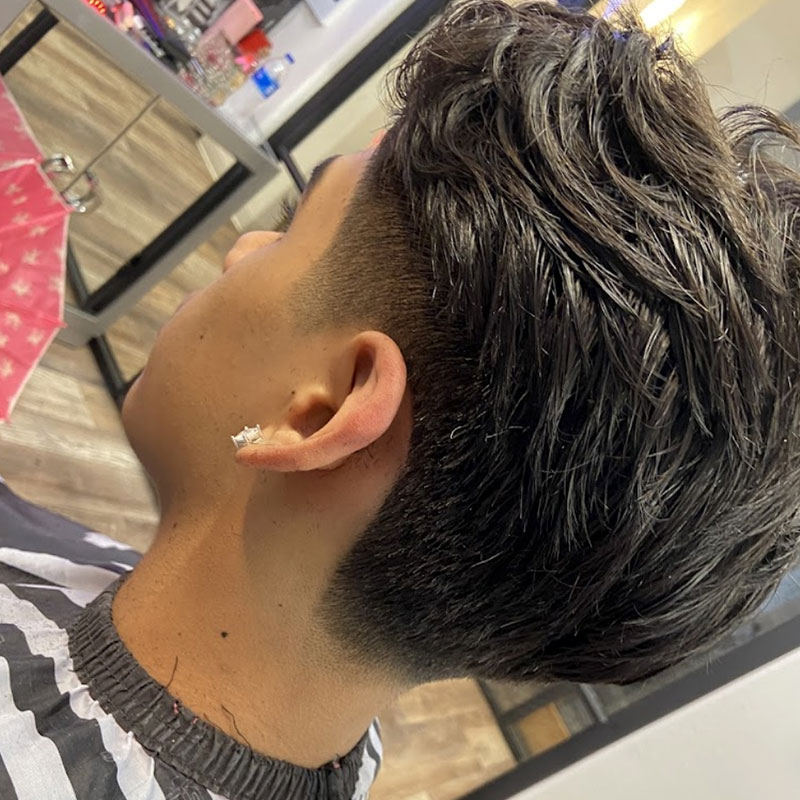 Men's haircut showcasing a stylish, textured top with a fade on the sides, reflecting modern grooming trends at Joni's Gentleman's Cuts barber shop.