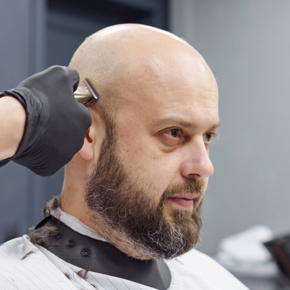 Barber edging a client's head with clippers during a head shave in Lone Tree, CO