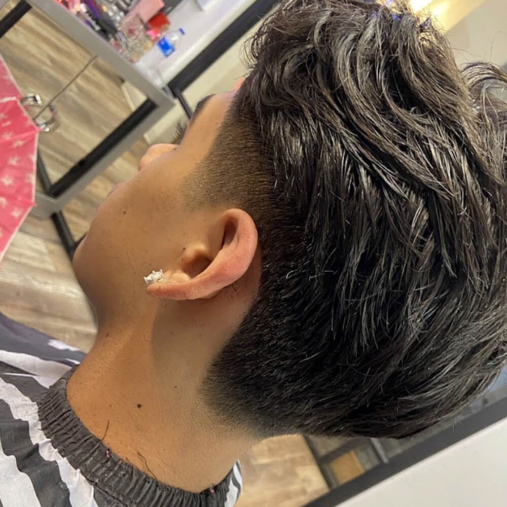 Close-up back view of a man's fresh taper fade haircut with thick, textured hair on top.